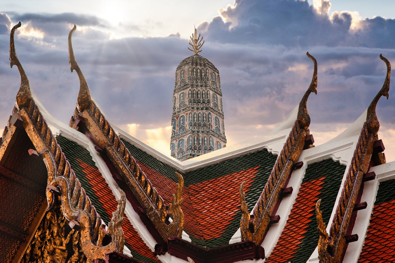Bangkok skyline at sunset with traditional Thai temple rooftops in the foreground